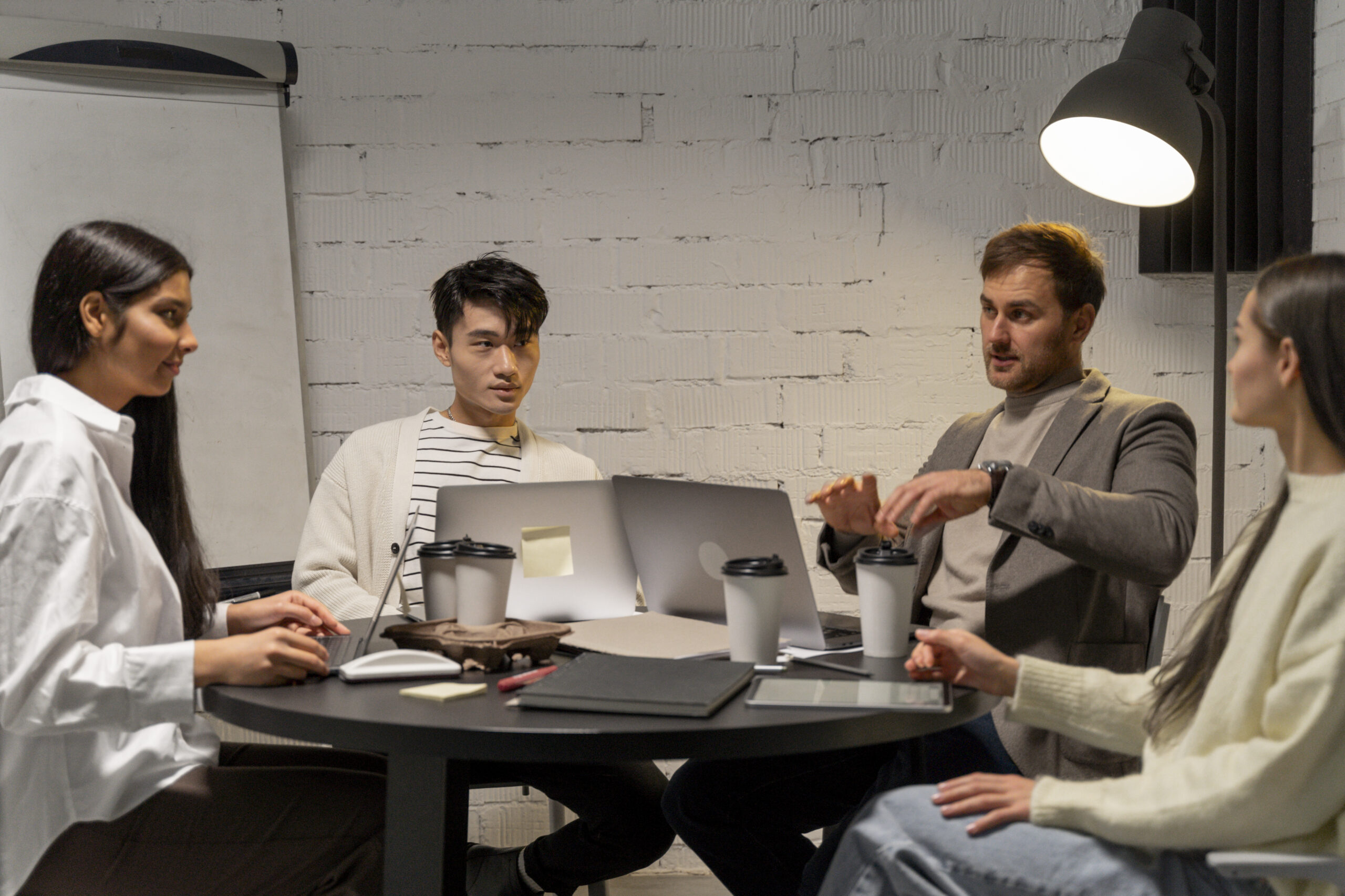 Focused group having a meeting at a round table with laptops.