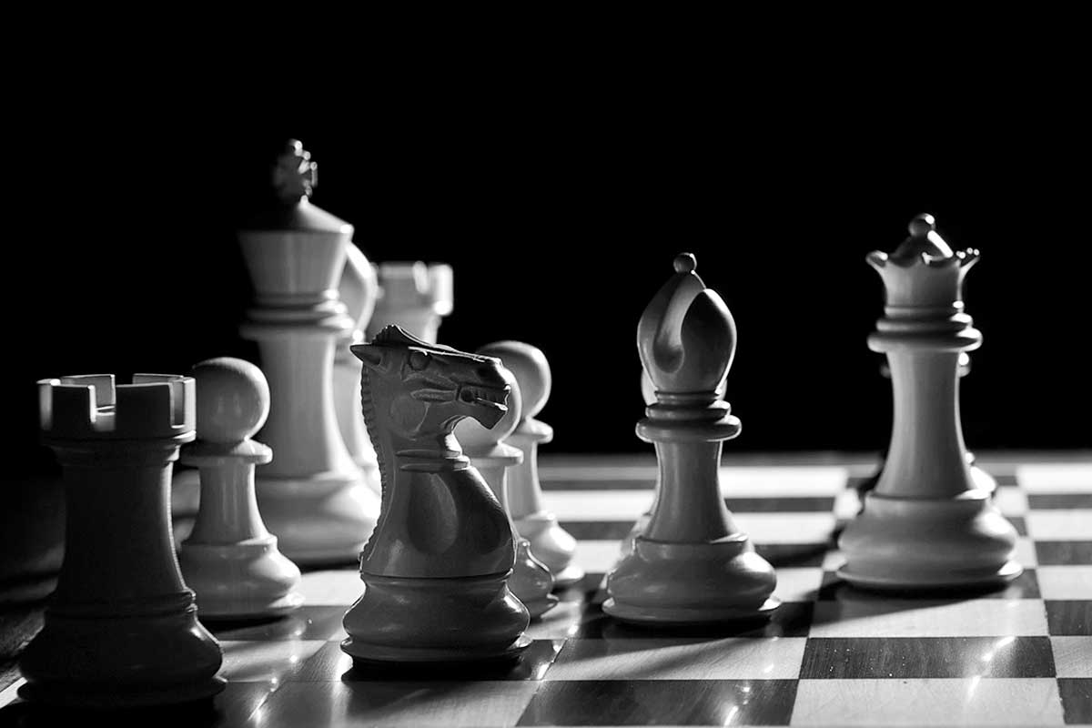 White chess pieces lit dramatically against a dark background for contrast.
